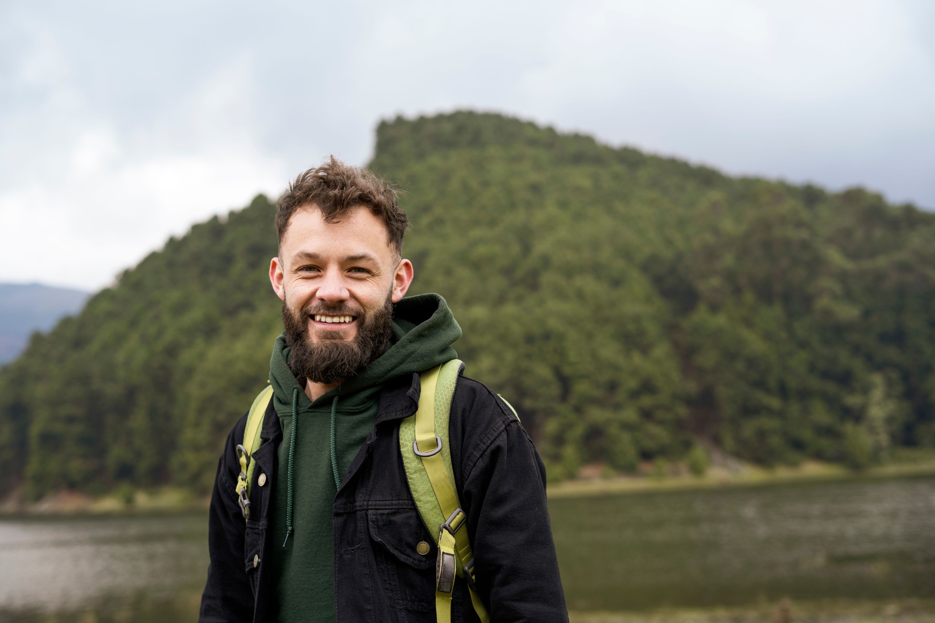 Retrato de un joven con barba sonriendo a la cámara en un parque natural